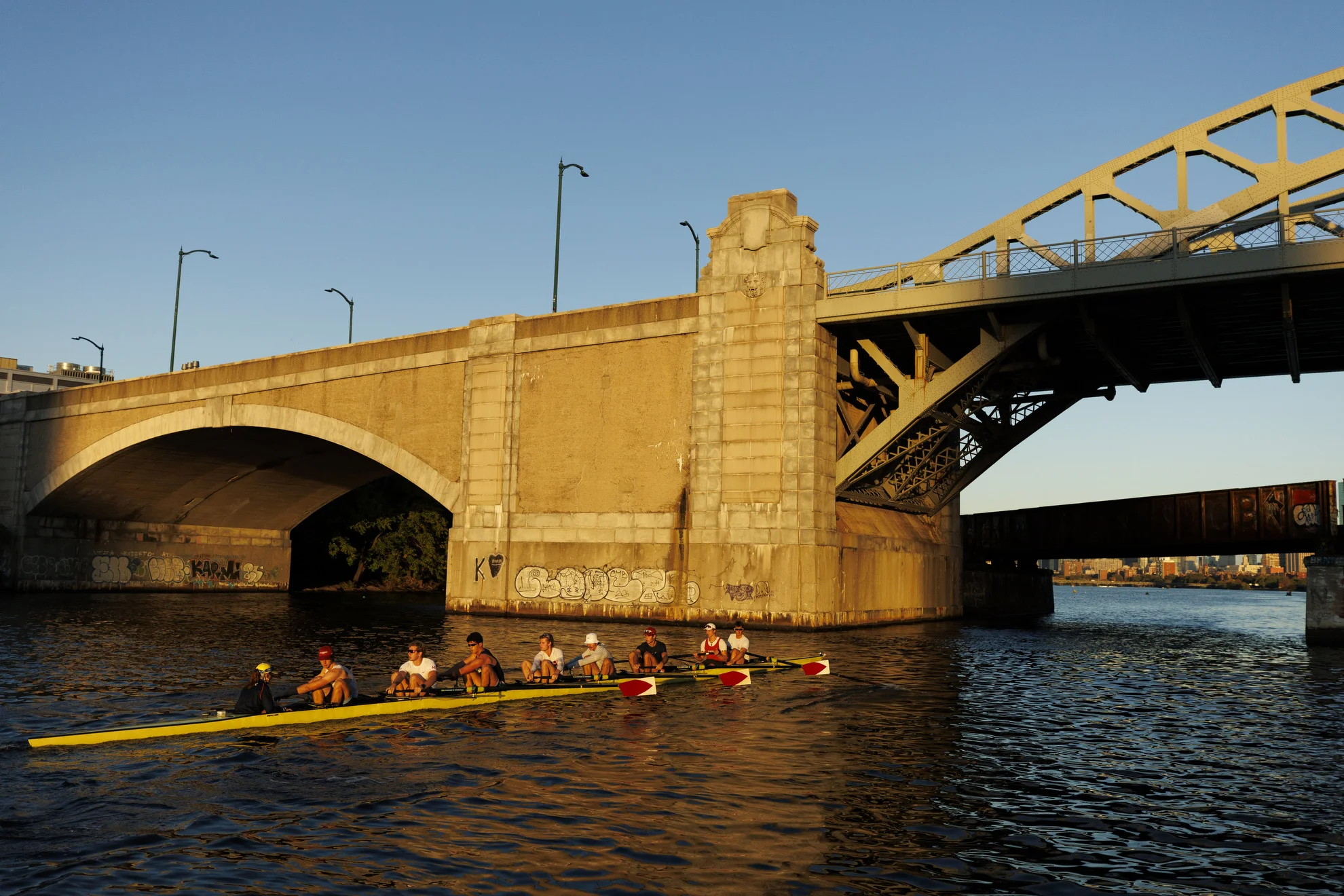 Members of Harvard’s men’s heavyweight rowing team pass under the Boston University Bridge.