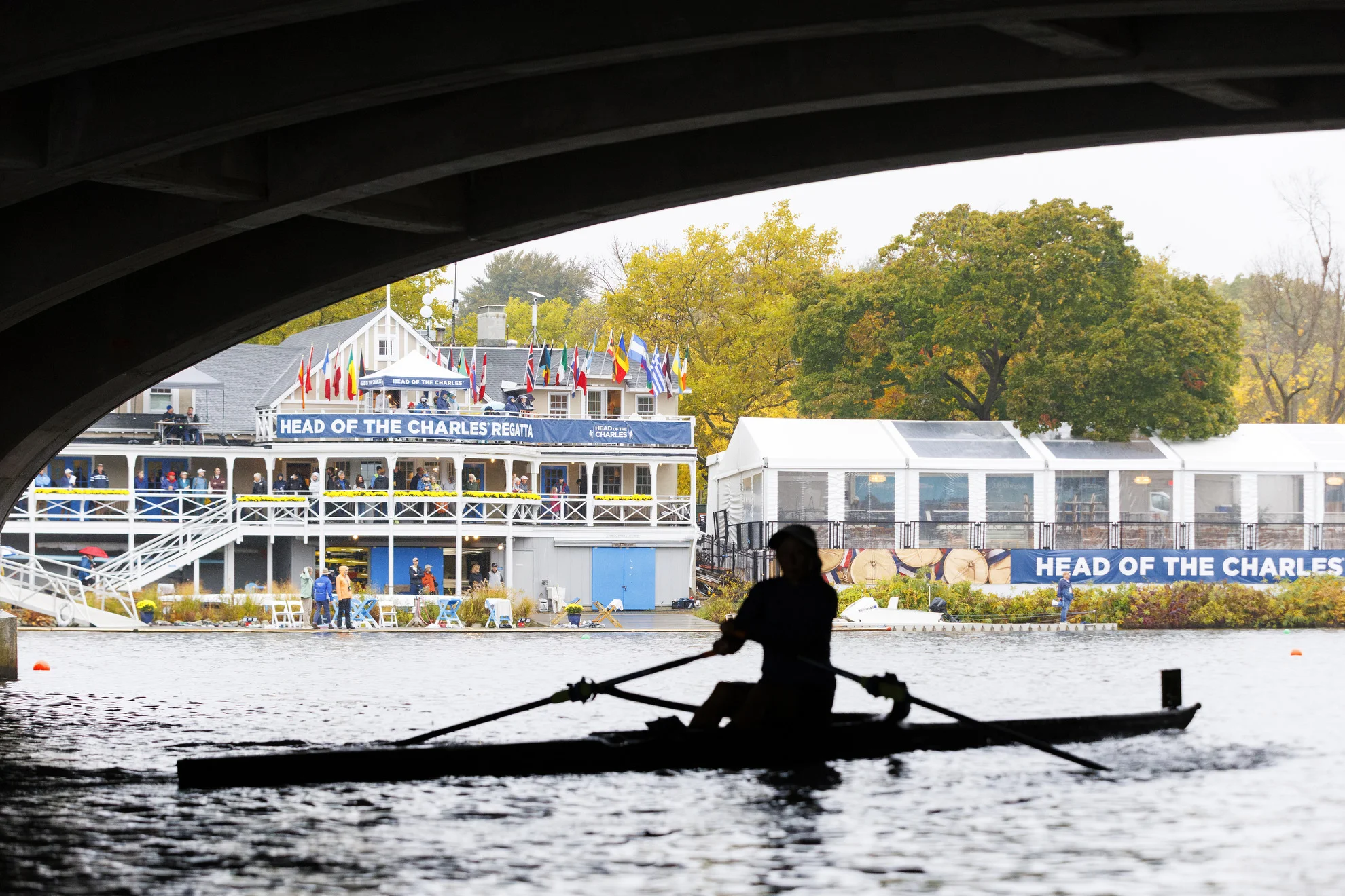 A silhouetted rower passes under Eliot Bridge in front of the Cambridge Boat Club.