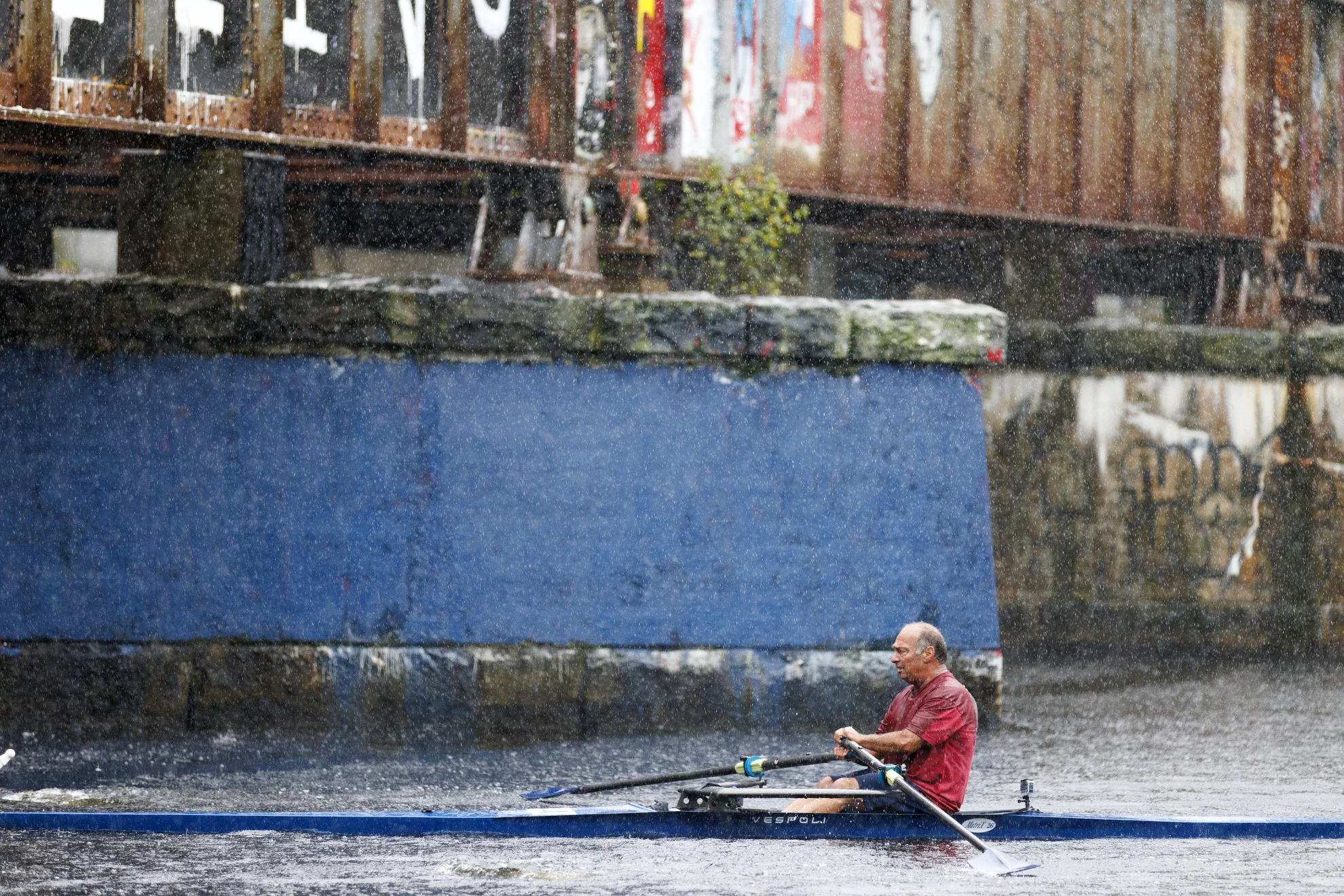 A racer approaches the Boston University Bridge in heavy rain during the first day of the Head of The Charles regatta.